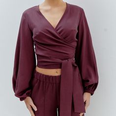 This stylish blouse features a puffy sleeve wrap design in a chic burgundy hue. It boasts a flattering V-neck in the front and a closed back and is crafted from 100% soft and breathable Tencel. The cinched waist flatters your figure, creating a feminine and flattering silhouette. Consciously produced in limited quantities in our own atelier in Romania. Designed to fit sizes ranging from XS to L, you can find your perfect fit and embrace comfort and style. 100% Tencel. Wash at 30 degrees, medium heat ironing. Our recommendation for washing clothes is to use either a mild detergent or one specifically designed for wool and silk fabrics. Conventional "color detergents" often contain enzymes that can break down the fibers or fade the colors. While they may work well with cotton, they have the Knit Loungewear, Shirt Blouses Women's, Silk Fabrics, Stocking Fillers For Her, Versatile Wardrobe, Holiday Party Outfit, Stylish Blouse, Puffy Sleeves, Tailored Pants