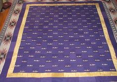 a purple and gold blanket on top of a bed