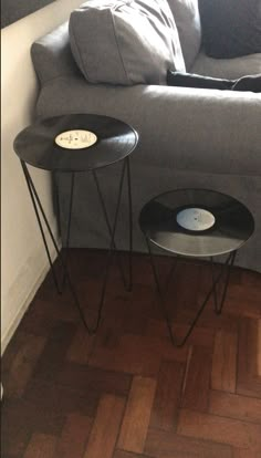 two black tables sitting on top of a wooden floor next to a gray sectional couch