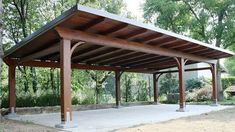 a covered area in the middle of a park with trees and bushes behind it,