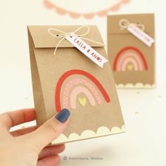 a hand holding a small brown bag with a rainbow on it