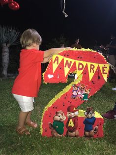 a young child standing in front of a large number seven sign with cartoon characters on it