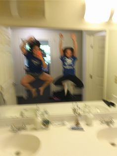 two people jumping in the air over a bathroom sink