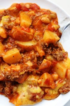 a white plate topped with pasta and meat covered in sauce