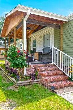 a porch with steps leading up to it and flowers growing on the lawn next to it