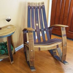 a wooden rocking chair next to a small table with a glass of wine on it