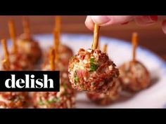 a person is picking up some appetizers from a plate with toothpicks