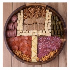 a wooden platter filled with different types of meats, cheese and crackers