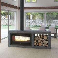 a fire place in the middle of a living room filled with furniture and large windows