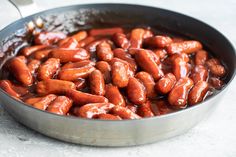 a pan filled with hot dogs covered in sauce