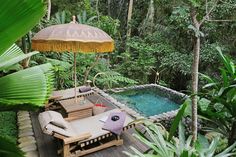 an outdoor pool with lounge chairs and umbrella in the middle of it surrounded by greenery