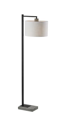 a floor lamp with a white shade on it and a black metal frame around the base