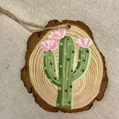 a piece of wood with a cactus painted on it and pink flowers in the center