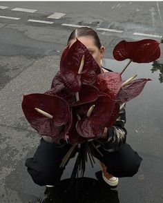 a woman kneeling down next to a puddle with flowers in her hands on the ground