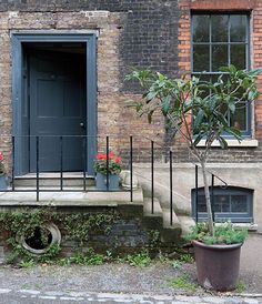 an old brick building with a planter and potted tree in front