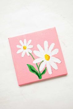 a pink square with white daisies painted on it