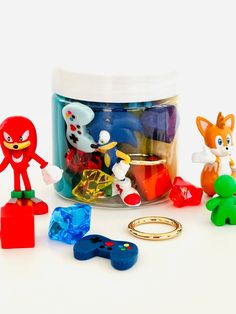 an assortment of plastic toys and figurines in a jar on a white surface