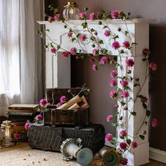 a fireplace with pink flowers on it next to an old trunk and other items in front of the fire place