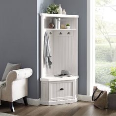 a white coat rack sitting in the corner of a room next to a chair and potted plant