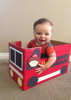 a baby sitting in a fire truck toy box