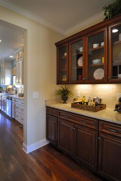 a large kitchen with wooden cabinets and white counter tops, along with hardwood flooring