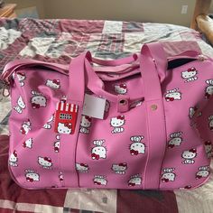 a pink hello kitty bag sitting on top of a bed