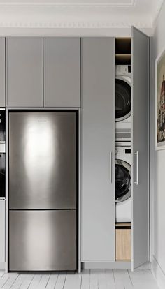 a stainless steel refrigerator freezer sitting inside of a kitchen next to a washer and dryer