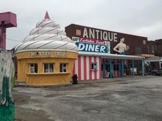 an ice cream cone sits in the middle of a parking lot next to a building