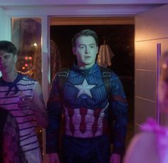 a man dressed as captain america standing in front of a mirror with his hands on his hips