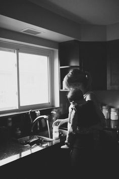 a woman holding a child while standing in a kitchen