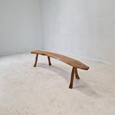 a wooden bench sitting on top of a white floor next to a wall in an empty room