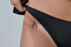 a woman's stomach with tattoos on the side and an arrow tattoo on her lower back