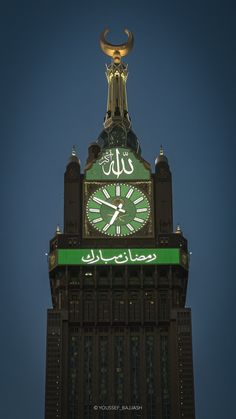 a large clock tower with a green and white sign on it's side at night