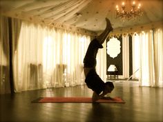 a person doing a handstand on a yoga mat in front of a chandelier