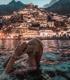 a woman floating in the water with her head above her face and buildings behind her