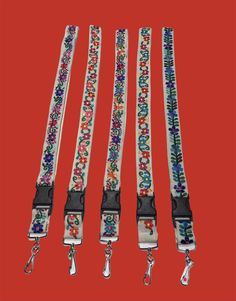 four lanyards with floral designs on them are lined up against a red background