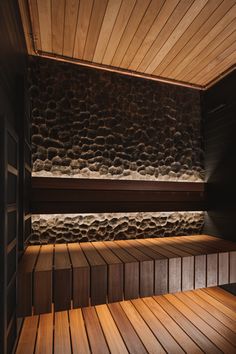 an empty sauna with wood flooring and stone walls