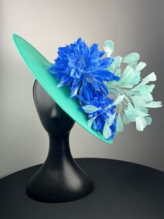 An oversized aqua woven base with beautiful periwinkle dahlias and aqua feathers. Sits on a comfortable white headband. Ships in a high quality storage box. One of a kind.  Perfect for Kentucky Derby, Royal Ascot, church, weddings, just for fun. Blue Hat With Feather Trim For Spring, Blue Feather Trim Headpiece For Kentucky Derby, Blue Feather Fascinator For Summer, Blue Feathered Fascinator For Summer, Elegant Turquoise Fascinator For Races, Blue Feathered Fascinator For Spring, Blue Feather Headpiece For Summer, Luxury Turquoise Fascinator For Spring, Blue Feathered Headpieces For Summer