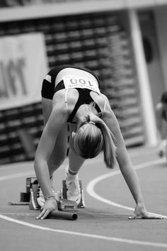 a woman bending over on top of a race track