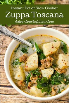 a bowl of soup with meat, potatoes and spinach on a wooden table next to a leafy green plant