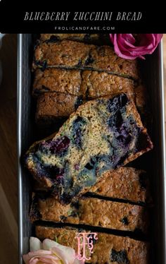 blueberry zucchini bread in a pan with flowers on the side and text overlay that reads, blueberry zucchini bread