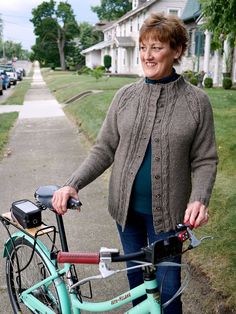 a woman standing next to her bike on the sidewalk