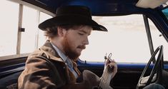 a man sitting in the driver's seat of a car while holding a guitar