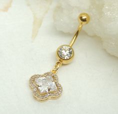 14g gold plated surgical steel belly ring features a golden floral charm accented with large diamond shape in the center. Belly ring measures 1 5/8 inches long total length. Barbell is 14g gold plated surgical steel with a clear crystal gem. For Belly Button Rings: https://www.etsy.com/shop/AllAboutClass?section_id=18474235&ref=shopsection_leftnav_1 For Add a Charm Belly Rings: https://www.etsy.com/shop/AllAboutClass?section_id=14180524&ref=shopsection_leftnav_2 For charms and supplies s Elegant Gold Belly Rings, Elegant Gold Belly Rings Gift, Belly Button Jewelry, Dangle Belly Rings, Prom Earrings, Navel Piercing, Button Rings, Body Piercings, Navel Rings