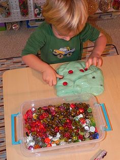 a little boy that is sitting at a table with some beads in front of him