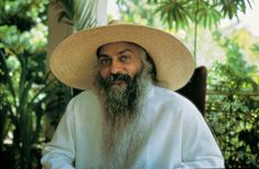 an old man with a long beard wearing a straw hat and sitting in a chair