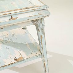 an old wooden table with peeling paint on the top and bottom, against a white background