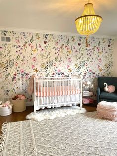 a baby's room with floral wallpaper and rugs