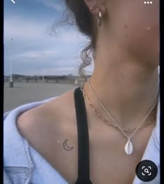 a woman wearing a neck tie and two necklaces on her chest, with the sky in the background