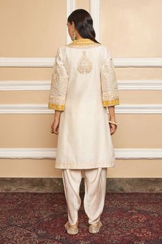 Ivory short kurta featuring a Mandarin collar, three quarter sleeves, and Kashmiri tilla with gota applique embroidery on the yoke. Paired with a matching dhoti pant crafted from Bamberg satin., Fit: Relaxed Semi-stitched Jamawar Sets With Intricate Embroidery, Short Kurta With Dhoti Pants, Ankle-length Fitted Kurta With Cutdana, Semi-stitched Beige Kurta With Intricate Embroidery, Semi-stitched Ankle-length Kurta With Cutdana, Kurta Patterns, Short Kurta, Dhoti Pants, Embroidered Shorts